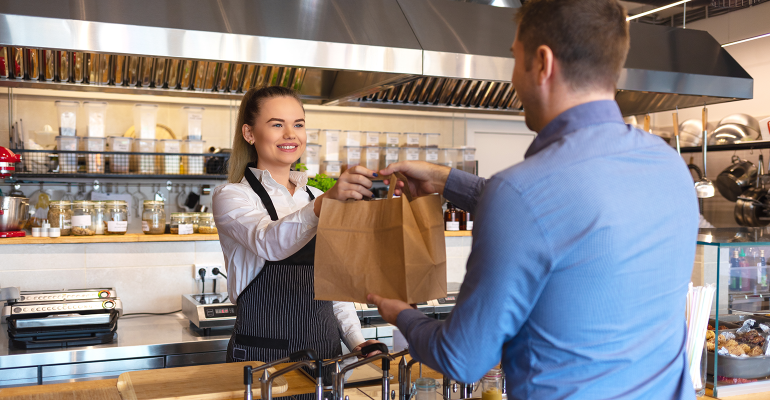 Happy-waitress-waring-apron-serving-customer-at-counter-in-small-family-eatery-restaurant.-Small-business-and-entrepreneur-concept-with-woman-owner-in-eatery-with-takeaway-service-delivery-1127824238_5800x3866.png