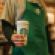 A Starbucks barista holding a reusable coffee cup.